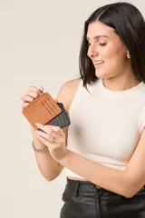 Tarjetero minimalista de ecocuero color marrón y negro, con cierre superior y ranuras externas.