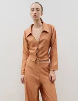 Camisa de manga larga color marrón con textura arrugada, cuello clásico y cierre frontal mediante lazos para anudar.