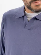 Buzo tejido de punto color beige, con cuello polo y escote en V profundo, de manga larga con puños acanalados.