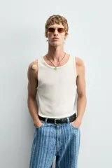 Camiseta tipo tank top de corte slim fit, color blanco hueso, con cuello redondo amplio y sisas terminadas con pespunte contrastante en color oscuro.