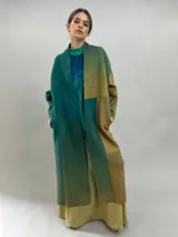 Tapado largo de lana merino afieltrada con diseño de paneles en degradé de tonos verdes y ocres. Presenta hombros caídos, mangas rectas, bolsillos laterales y cierre frontal con broches ocultos.