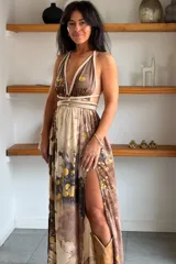Vestido largo de seda con estampado abstracto en tonos marrones, beige y destellos dorados, con escote en V profundo, tirantes de cuerda anudados al cuello y la cintura, y tajo lateral en la falda.