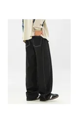 Pantalón de jean negro de corte muy ancho (baggy), con costuras exteriores en hilo blanco contrastante.