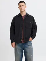 Sobrecamisa de manga larga confeccionada en pana de algodón, con cuello camisero, cierre frontal de botones, puños abotonados y un bolsillo en el pecho. Presenta un corte relajado y textura acanalada.