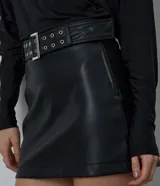 Pollera mini de tiro alto confeccionada en poliuretano con acabado liso. Presenta un diseño ajustado y cuenta con un cinturón incorporado con ojales metálicos y hebilla frontal.