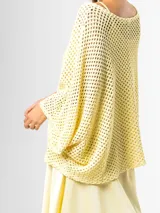 Sweater de tejido en red color amarillo mantequilla, con diseño oversize y amplio, mangas largas y caída holgada ideal para superposiciones.