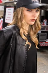 Campera de cuero negro con detalles de costuras decorativas en los bordes delanteros y mangas largas.