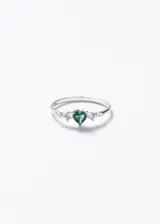 Anillo de plata 925 con diseño delicado, presenta una piedra de zirconia en forma de corazón de color verde en el centro, flanqueada por pequeñas piedras brillantes en los laterales.