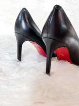 Zapatos clásicos de taco alto tipo stiletto, confeccionados en cuero negro con textura símil cocodrilo, suela roja y taco fino de 8,5 cm.