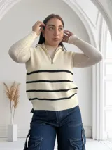 Chaleco de punto color crudo con rayas horizontales negras, cuello polo con cierre metálico y corte holgado.