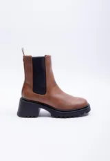 Bota marrón de símil cuero, con punta redondeada, pieza elastizada negra en los laterales y plataforma de 6cm.