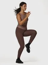 Calza deportiva de tiro alto en color marrón chocolate, confeccionada en tejido suave con tecnología Aloe Vera. Presenta un diseño ajustado que se adapta al cuerpo, ideal para actividades físicas o uso diario.