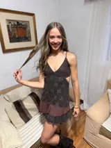 Vestido corto de tela metalizada en tono fucsia con reflejos dorados, con escote en V, diseño de top con triángulos, aberturas laterales en la cintura y doble volado irregular en el ruedo.
