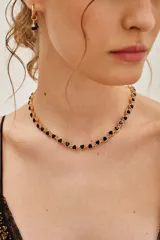 Collar tipo gargantilla con cadena dorada y dijes en forma de corazón de color negro.