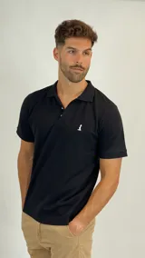 Chomba de piqué color negro, con cuello clásico, cierre frontal de dos botones y logo bordado en el pecho.