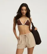 Short de playa color beige, confeccionado en viscosa y poliamida, con diseño holgado, bolsillos laterales, cintura elástica con cordón de ajuste tipo lazo y detalle de botones frontales.