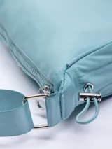 Riñonera semicircular color celeste de nylon con correa regulable, cierre superior y elásticos en los laterales.