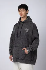 Buzo canguro oversize de algodón friza con efecto de teñido artesanal desgastado. Presenta capucha con cordones negros, bolsillo frontal tipo canguro y estampa pequeña de Popeye en el pecho.