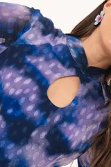 Vestido largo de manga larga con terminación campana, de color azul y violeta con estampado tie-dye, cuello mao con ojal y tajo frontal. Cuenta con flecos en el ruedo y tajo en la pierna.