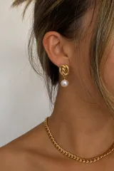 Aros colgantes dorados de acero con diseño entrelazado en la parte superior y una perla sintética colgante en forma de esfera.