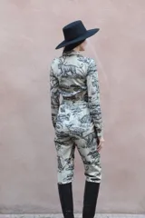 Mono largo de gabardina color beige con estampado de tigres y árboles. Tiene cuello camisero, cierre frontal con botones, cintura elástica y bolsillos laterales.