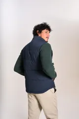Chaleco puffer de color azul marino, con cierre frontal completo y cuello alto. Presenta un diseño acolchado horizontal y el logo de la marca bordado en el pecho.