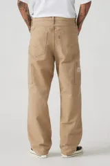 Pantalón de jean color beige, de corte recto y holgado, con bolsillos laterales y traseros.