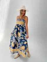 Vestido largo de algodón italiano con estampado floral en tonos azul, amarillo y blanco. Tiene escote cuadrado, corte imperio y elástico en la espalda.