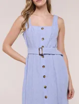 Vestido midi abotonado verde melange, con escote recto, tirantes anchos y falda de calce recto con vuelo sutil. Tiene abotonadura frontal completa con botones estilo carey, cinto textil con hebilla para ajustar la cintura y bolsillos laterales.