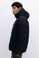 Campera puffer de diseño acolchado, con cuello elevado, capucha ajustable con cordón, cierre frontal, bolsillos laterales con cierre y puños elásticos.