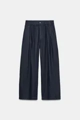 Pantalón de tiro medio confeccionado en 100% lino, color azul marino, de corte ancho con pinzas en el delantero, cintura elástica con trabillas y cierre frontal con cremallera y botón.