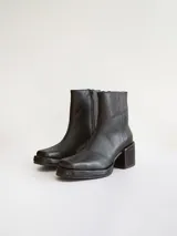 Bota corta de cuero negro con punta cuadrada y taco bloque texturizado. Presenta cierre lateral y costura central en el empeine.