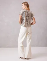 Blusa de manga corta cubierta de lentejuelas en tono champagne, con cuello redondo a la base y forro interno a tono.