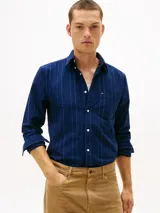 Camisa azul oscuro de corte regular con patrón de raya diplomática blanca y roja, confeccionada en puro algodón Oxford. Cuenta con cuello abotonado, cierre frontal con botones, bolsillo de parche en el pecho con logo bordado y mangas largas con puños abotonados.