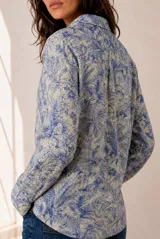 Camisa de manga larga con cuello clásico y cierre frontal de botones, con estampado botánico de hojas en tonos azules y blancos.