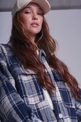 Sobrecamisa de franela color beige con estampado a cuadros en tonos marrones y azules, de corte holgado, con cuello clásico, cierre abotonado y bolsillos delanteros con solapa.