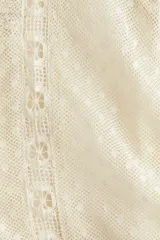 Blusa de manga larga confeccionada en malla plumeti color crema, con detalles de encaje, bordados y alforzas. Presenta cuello redondo, cierre con botón en la nuca y un corte con frunces laterales en la cintura que aportan volumen al bajo.