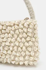 Bolso de mano pequeño con diseño estructurado, completamente cubierto de abalorios perlados. Cuenta con un asa superior también decorada con cuentas y cierre de cremallera metálica.