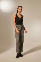 Pantalón de jean recto de tiro alto, color gris lavado con efecto acid wash. Presenta detalles de strass o apliques brillantes a lo largo de las costuras laterales exteriores.