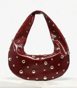 Bolso hobo de cuero sintético color bordó, con tachas plateadas.
