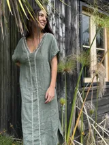 Vestido largo de lino celeste, de corte recto y holgado, con escote en V y detalles de bordado rojo en el frente.
