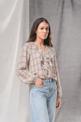 Blusa de gasa a cuadros en tonos beige y marrón, con escote en V adornado con volados en cascada, mangas largas con puños elásticos y ajuste holgado.