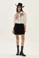 Falda corta de cuero color marrón, con diseño de flecos largos desmontables que cubren toda la prenda. Presenta un estilo western con cierre en la cintura.