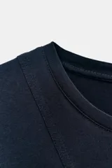 Camiseta azul marino de manga corta con cuello redondo. Presenta un diseño con paneles combinados a tono y un bajo con volantes amplios.