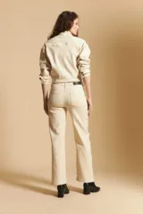 Pantalón de corte recto y tiro medio, color marrón, con detalle de tachas metálicas a lo largo de las costuras laterales y tajos en el ruedo.