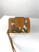 Mini billetera de cuero marrón con solapa frontal que presenta un grabado de un búho. El cuerpo de la billetera está confeccionado en cuero con pelo natural en tonos marrones y manchas doradas.