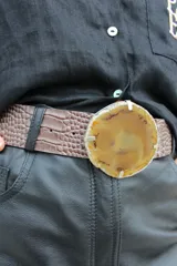 Cinto de cuero azul con hebilla circular de piedra ágata con borde dorado.