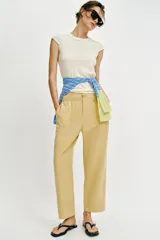 Pantalón de tiro medio color amarillo, con cintura elástica, bolsillos de plastrón en el delantero y pernera holgada que se estrecha hacia el tobillo. Cuenta con cierre frontal de cremallera y botón.