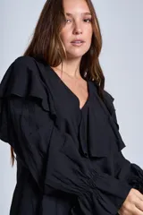 Blusa de color marrón con escote en V, mangas largas abullonadas con puños elásticos y detalles de volados en los hombros y el frente.