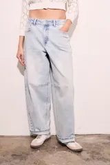 Jean de corte baggy con silueta barrel, tiro medio y lavado claro. Presenta costuras reforzadas en las rodillas y ruedo con doblez.